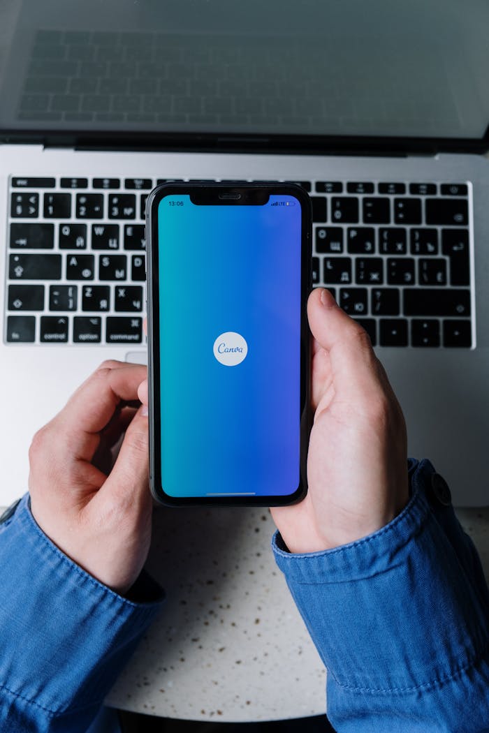 Mastering the First Impression: Your intriguing post title goes here Hands holding smartphone with app open, placed over laptop keyboard, technology concept.